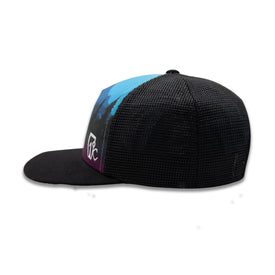 The Riveter Trucker by Icelantic Skis is a black mesh snapback hat with a flat brim and a vibrant front panel inspired by the Colorado mountains. Displayed from a side angle against a white background, it features white stylized lettering on the side and an adjustable snapback closure for comfort. Part of the Riveter Collection.