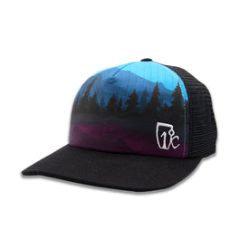 The Icelantic Skis Riveter Trucker is a black mesh snapback hat from the Riveter Collection, showcasing a vibrant mountain and forest design inspired by the Colorado mountains in blue and purple tones. It features a small white logo on the lower right of the front panel, and its adjustable snapback closure guarantees a comfortable fit.