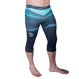 A person is wearing Icelantic 22/23 Mens WikMax Baselayer 3/4 Bottom leggings in a teal and black geometric pattern, made from WIKMAX fabric, while standing barefoot on a white background.
